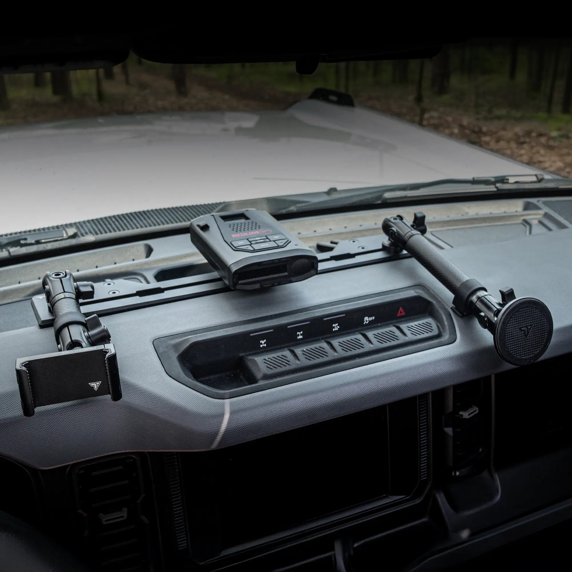 Dashboard photo of Ford Bronco with dash bracket installed that has phone mounts and a universal magnetic device mount with radar detector attached.